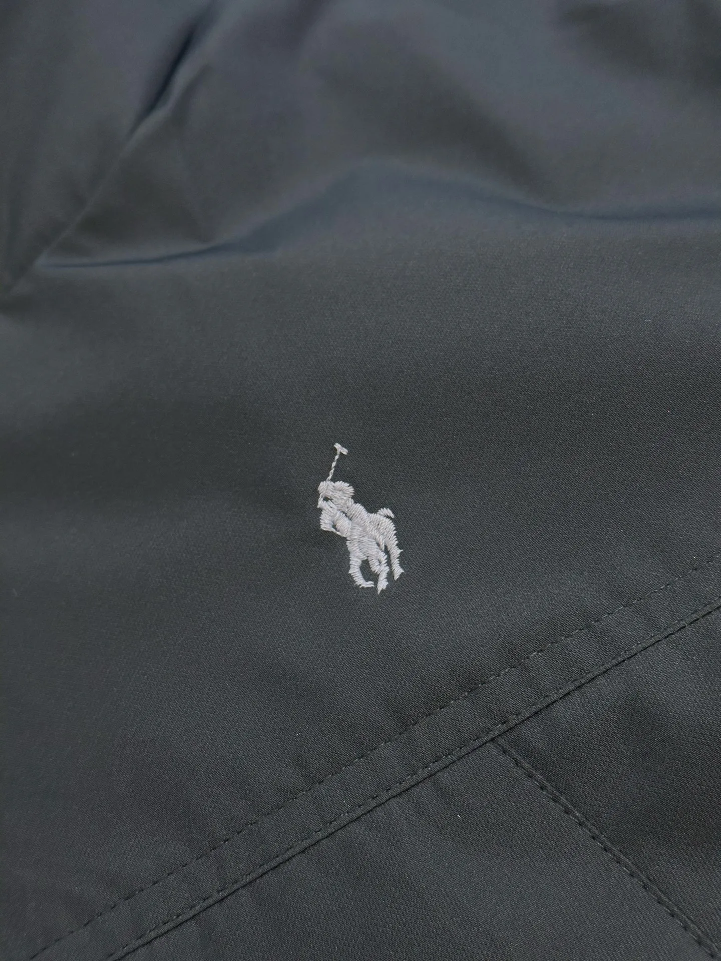 P970 Ralph Lauren logo hooded down jacket. The density of high-density nylon taffeta is about 210T-300T. The surface is smooth and slightly matte. It has excellent windproof and waterproof performance (with DWR water-repellent treatment). It has strong wrinkle resistance and is easy to care for. It is in line with the positioning of American casual "durable and practical".  The inner lining is made of 100% polyamide. The high-density and tight weaving process prevents fine lint from getting out of the gaps in the fabric. The smooth surface improves the putting on and taking off experience, and the excellent wear and tear resistance ensures damage caused by frequent use, while the light and soft texture does not affect the overall weight.  It uses 90 white duck down with a weight of 220g to ensure excellent thermal insulation performance. After strict screening and processing, the velvet is not easily drilled, ensuring durability. The classic jacket has a slightly loose fit, with slightly dropped shoulder lines (the shoulder width is 1-2cm wider than the standard fit). The length reaches the hips, and the sleeves are slightly tapered straight sleeves, taking into account freedom of movement and casual style.  The adjustable Velcro on the cuffs allows you to freely adjust the tightness according to the thickness of your wrist and personal preferences, effectively preventing cold wind from intruding, and improving the warmth performance. Two zippered pockets on the front are convenient for placing frequently used items, and the zipper design ensures that items are not easily lost. A built-in pocket on the left side of the chest provides a safe storage space for some small private items.  The drawstring design at the hem allows you to adjust the shape of the jacket according to your body shape and dressing needs. Whether it is loose and casual or slim and neat, you can easily control it.  Polo horse logo on the left chest: flat satin stitch embroidery (satin embroidery), using 100% polyester high color fastness embroidery thread (the color number is consistent with the brand's standard red color card), the stitch density is 12-15 stitches/cm, the outline of the horse logo is clear, and the details of the rider and horse are burr-free. Precise positioning through the template (12cm from the bottom of the collar and 8cm from the placket) ensures symmetry and centering.  size：s m l xl